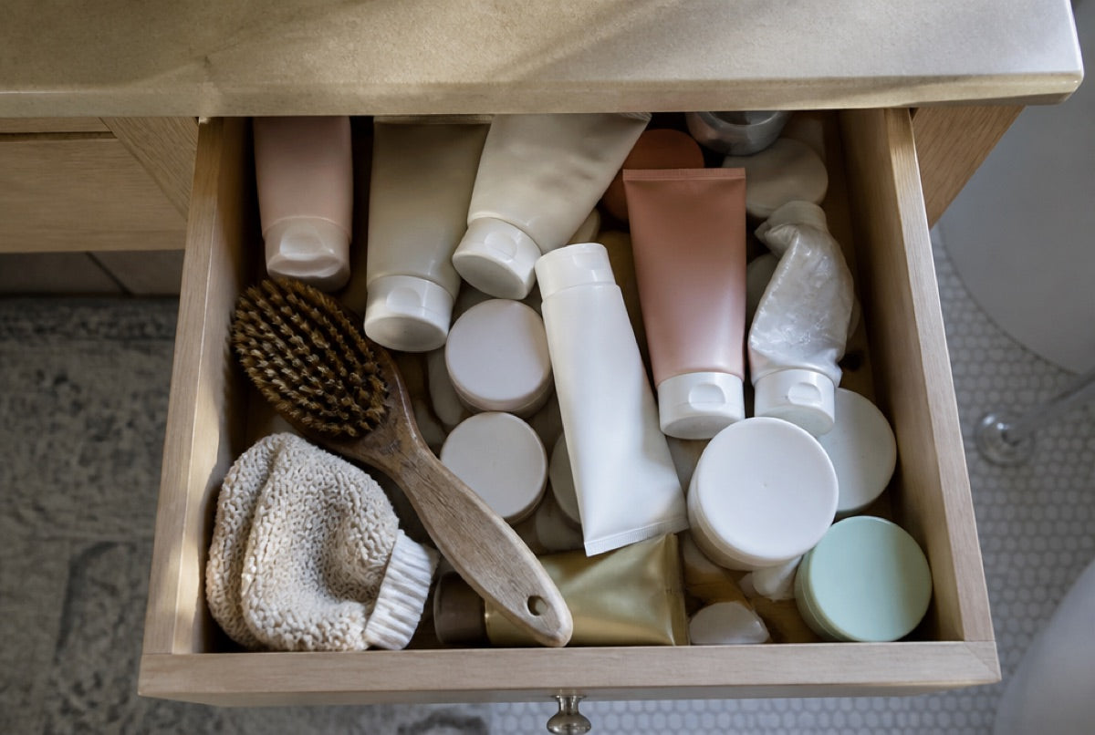 A bathroom drawer full of anti-cellulite creams, tubes and a dry brush